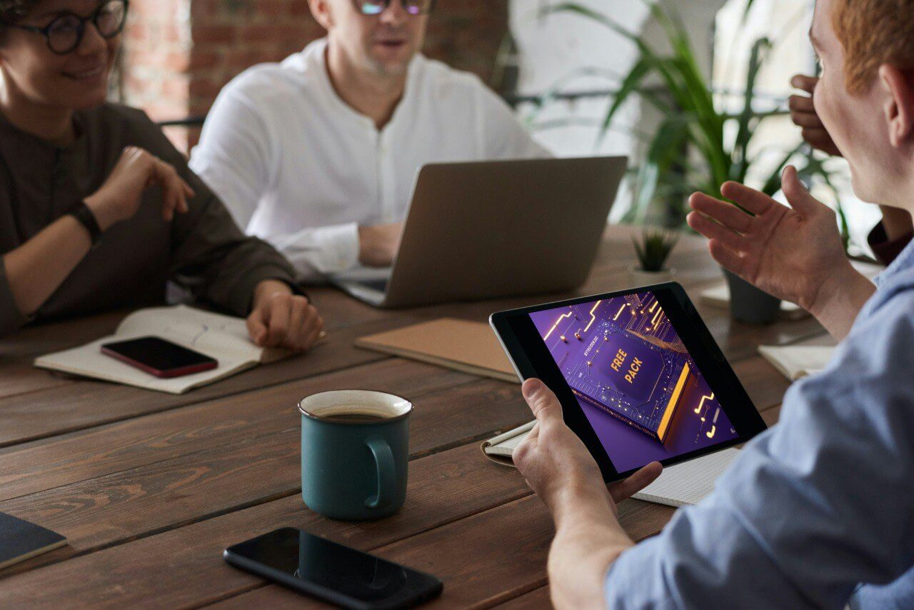 People in a meeting setting with a tablet displaying a 'Free PACK' course.