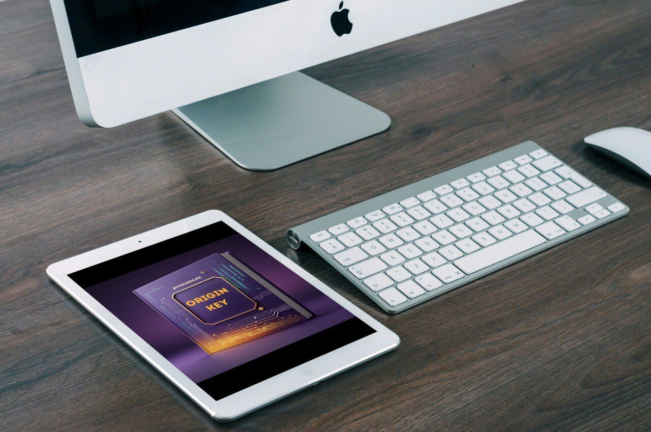 Computer setup with iMac, keyboard, and tablet with 'Origin Key' course on a wooden surface
