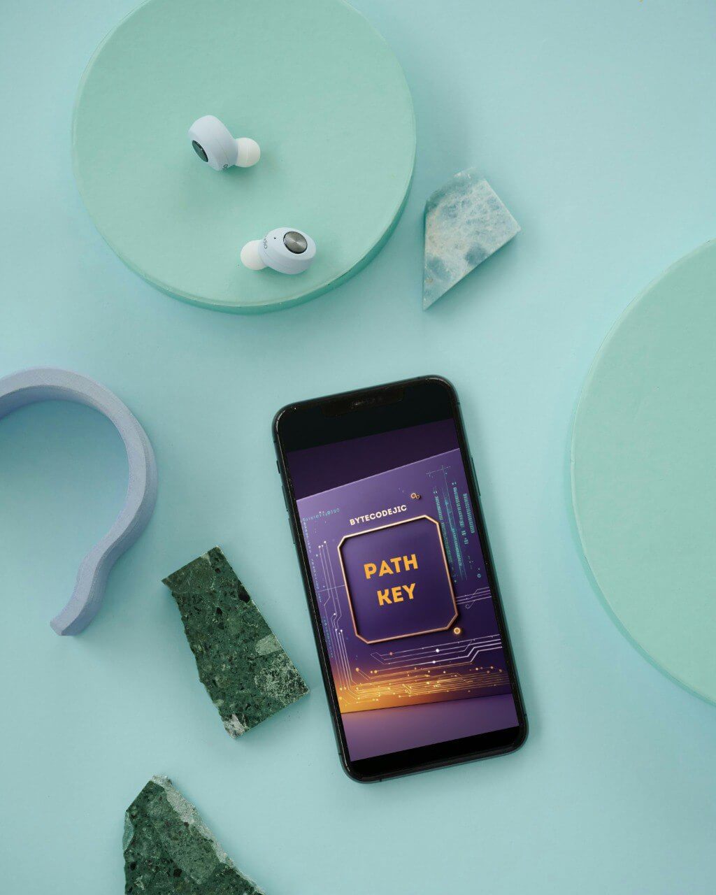 Phone with 'Path Key' course interface, wireless earbuds, and decorative stones on a light green background